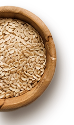 A wooden bowl filled with organic oats sits against a dark background. The oats are light in color, showcasing their natural, unprocessed texture, ideal for healthy meals and snacks.