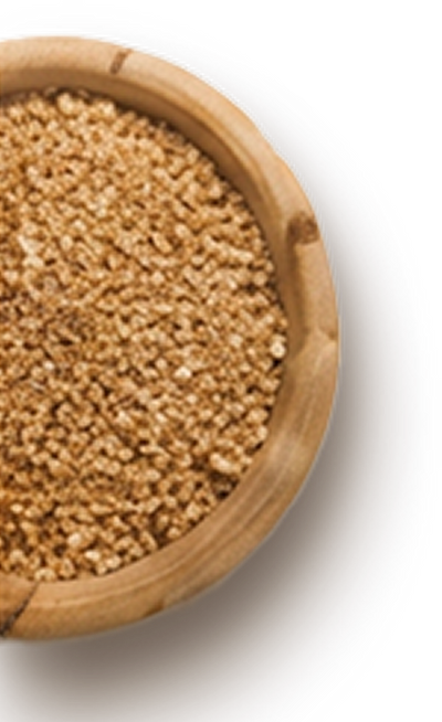A close-up view of a round wooden bowl filled with coarse, light brown sugar. The texture of the sugar granules is visible, showcasing a natural, unrefined appearance against a dark backdrop.