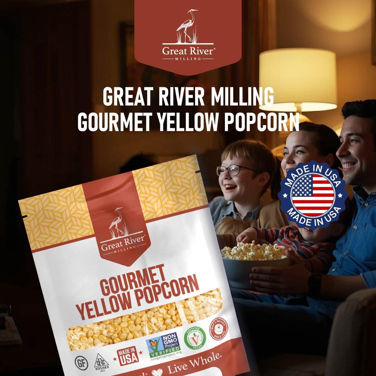 A bag of Great River Milling Gourmet Yellow Popcorn Kernels with a patterned yellow design and clear window, set against a cozy background with people enjoying popcorn