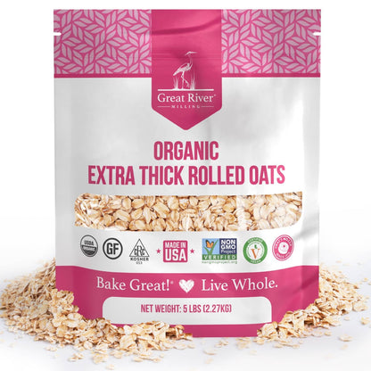 A 25 lb bag of Great River Milling Organic Extra Thick Rolled Oats, featuring a pink and white design with various certification logos and visible oats through a clear window