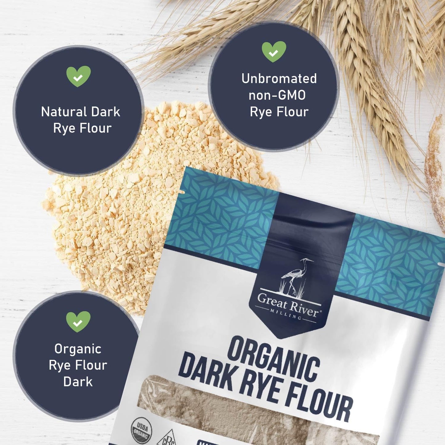 A 25 lb bag of Great River Milling Organic Dark Rye Flour is on a white surface with wheat stalks and flour piles. The packaging highlights its non-GMO and organic attributes