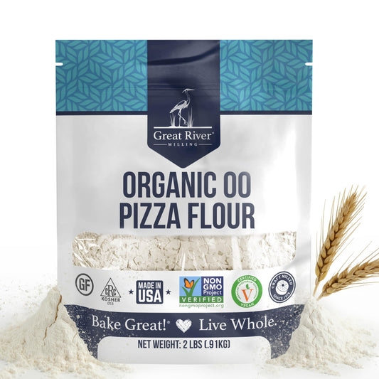 A 2-lb bag of Organic 00 Pizza Flour, crafted from high-quality organic wheat, rests in a mound of flour with two wheat stalks nearby. The package features certifications for organic, kosher, gluten-free, and non-GMO—ideal for creating an authentic Neapolitan pizza crust at home.