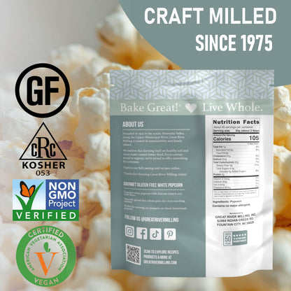 A bag of Great River Milling Gourmet White Popcorn Kernels is displayed against a backdrop of popped popcorn. The packaging features various certifications and nutritional information