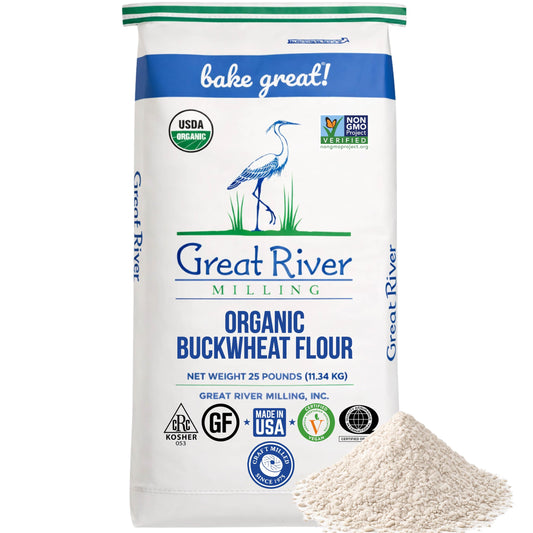 The 25 lb bag of Great River Milling Organic Buckwheat Flour features a white design with green accents, showcasing a heron illustration and multiple organic certifications