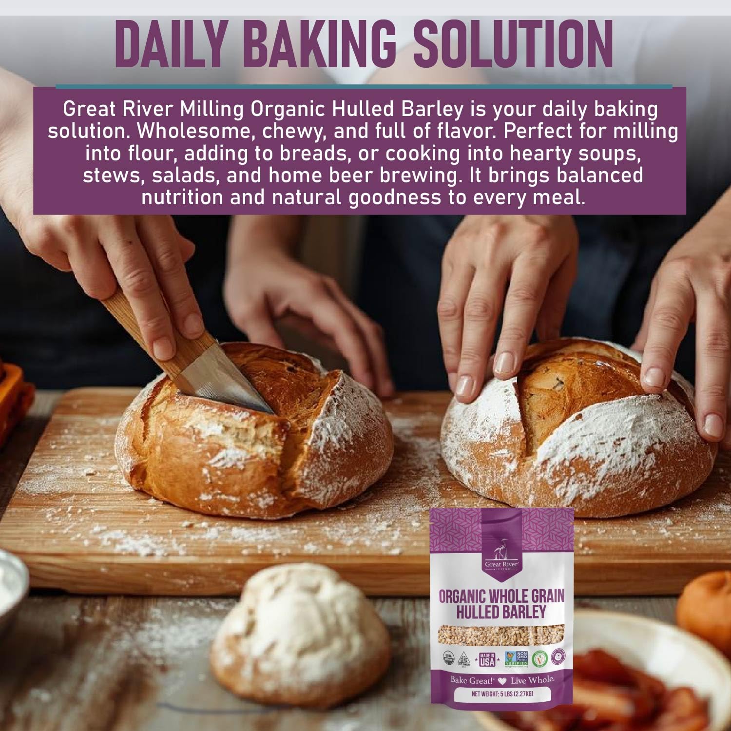Two hands slice crusty, round loaves of bread on a wooden board. A purple bag of Great River Milling Organic Hulled Barley is displayed in the foreground