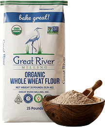 Bag of Great River Organic Whole Wheat Flour with a wooden bowl of flour beside it, brand text visible