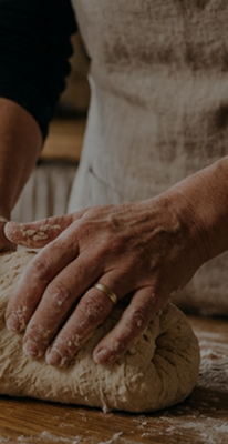 Hands kneading dough on a wooden surface
