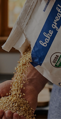 Grains pouring from a paper bag into cupped hands
