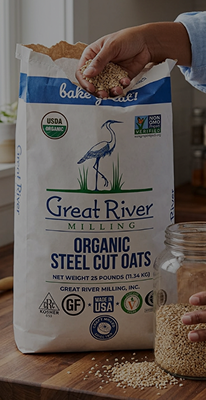 Hand pouring organic steel cut oats from a large Great River Milling bag into a glass jar